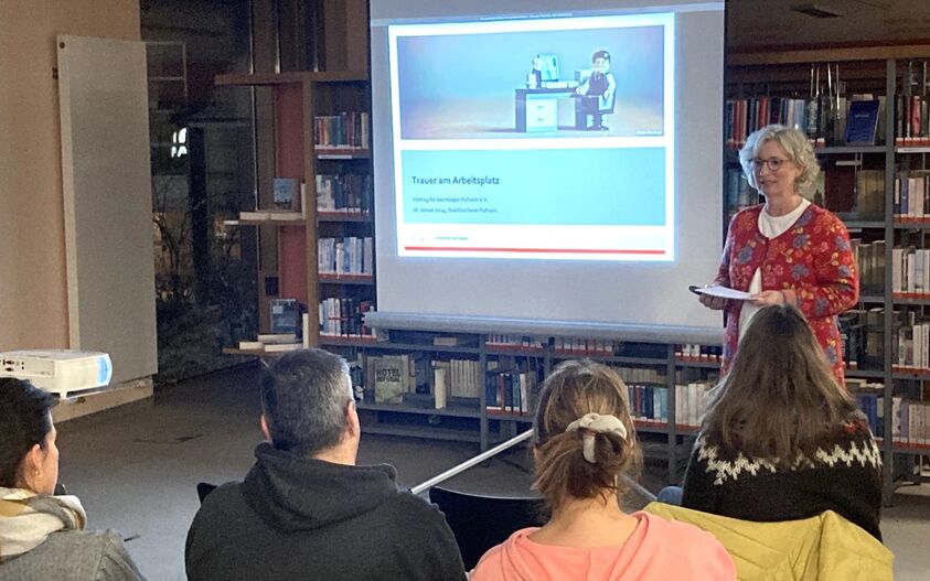 Eine Frau hält eine Präsentation vor einer Gruppe von Menschen.